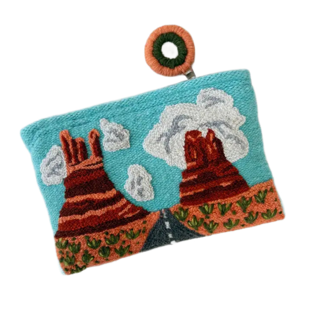Handmade pouch with embroidered designs of mountains and clouds on a white background