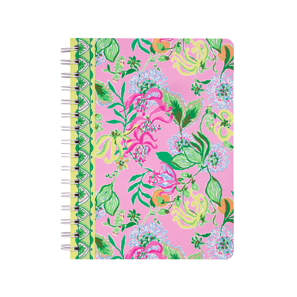 A spiral-bound notebook with a vibrant pink cover decorated with a colorful floral and botanical pattern, featuring green leaves, pink flowers, and yellow accents. The notebook is bound with silver metal wire on the left side and is photographed against a solid white background.