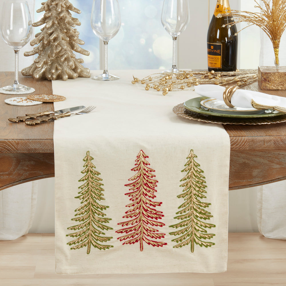 Table setting with a decorative table runner featuring embroidered trees on a wooden table.