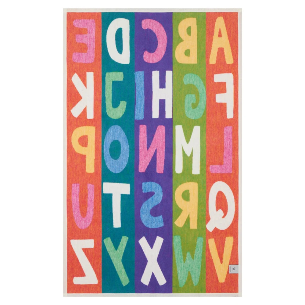 A colorful alphabet rug featuring the English alphabet in large, playful letters arranged vertically on vertical stripes of orange, teal, purple, yellow, green, and red, with a white border.