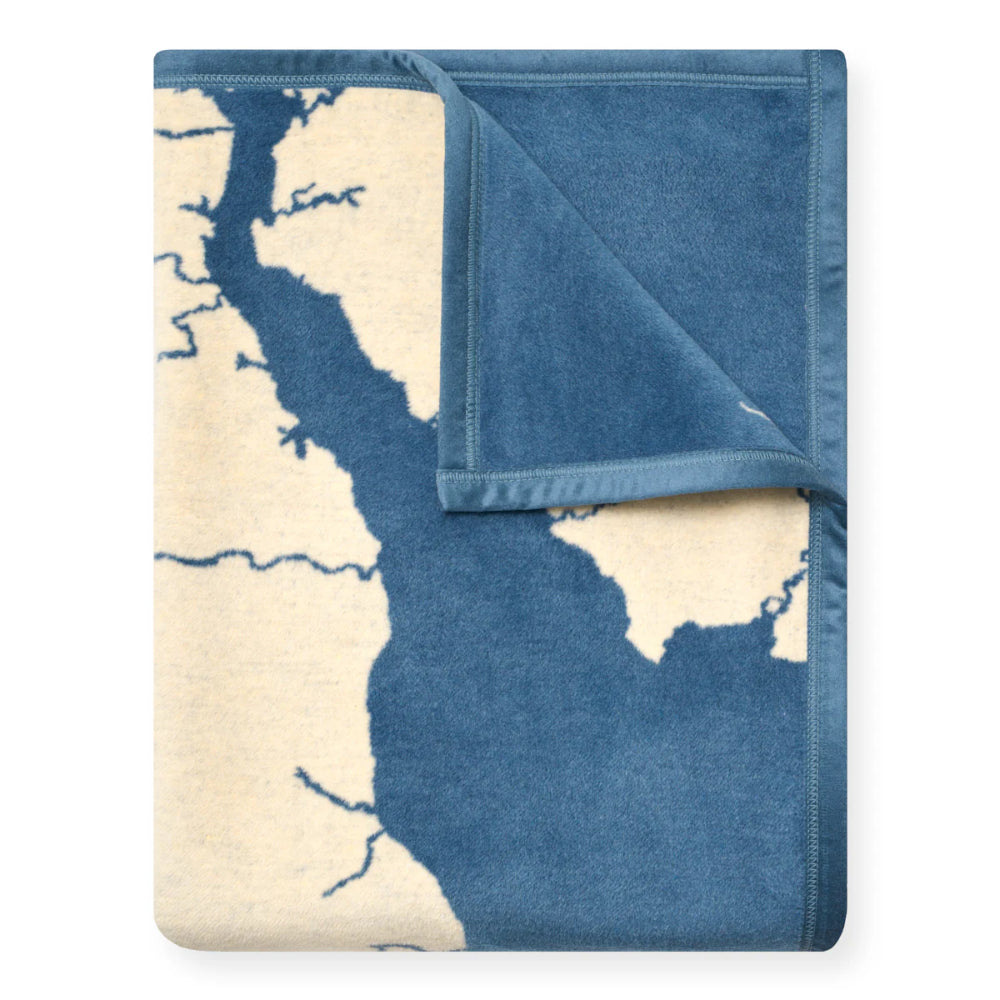 A folded throw blanket featuring a map design in shades of blue and cream, with a solid blue reverse side and stitched border, shown on a plain white background.
