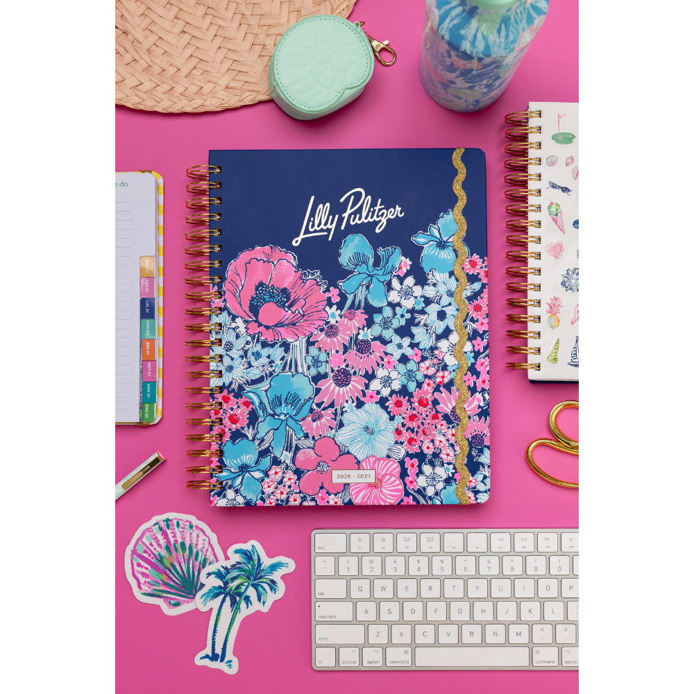 Floral notebook with 'Lilly Pulitzer' branding on a pink surface with stationery items.