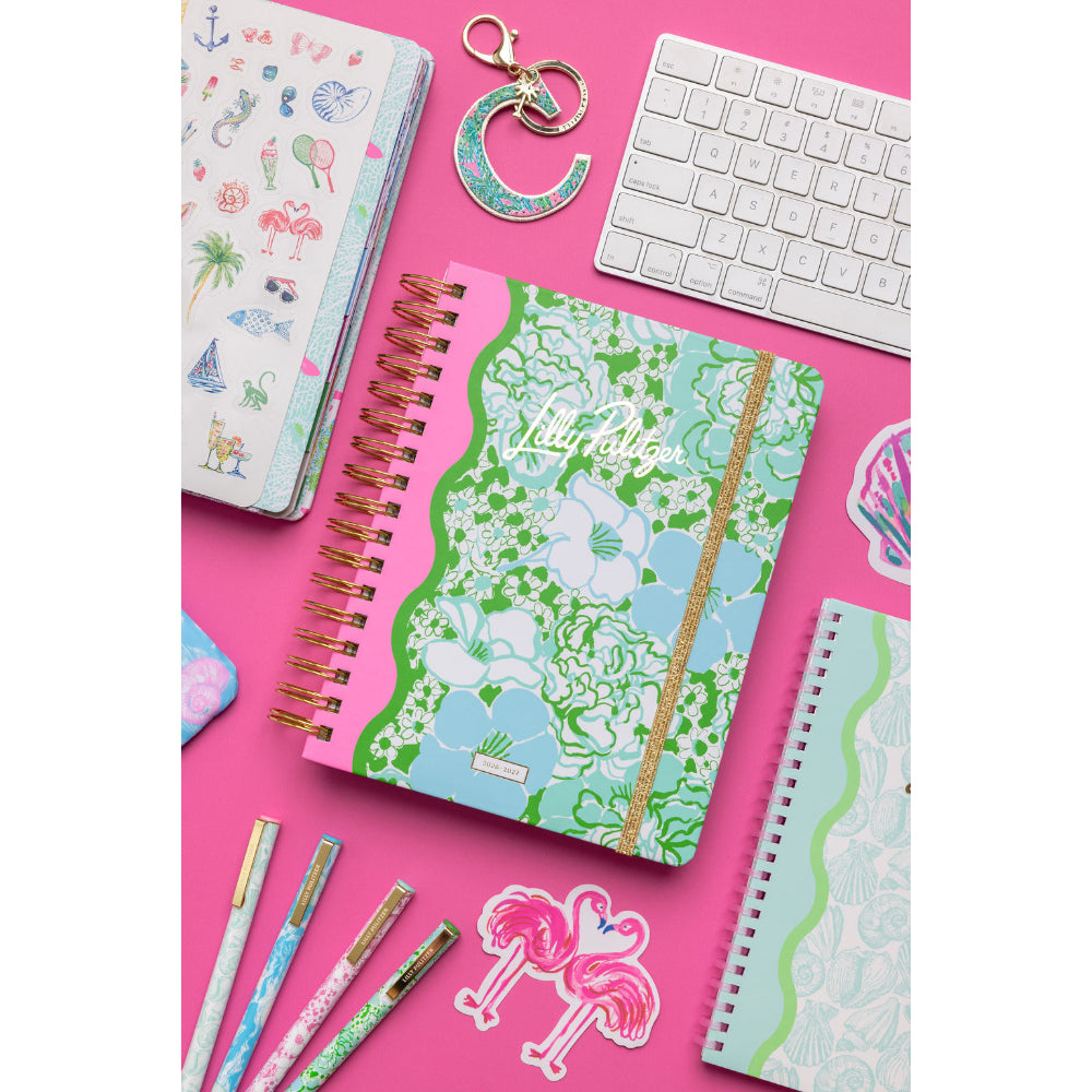 Colorful notebooks, pens, and a keyboard on a pink background