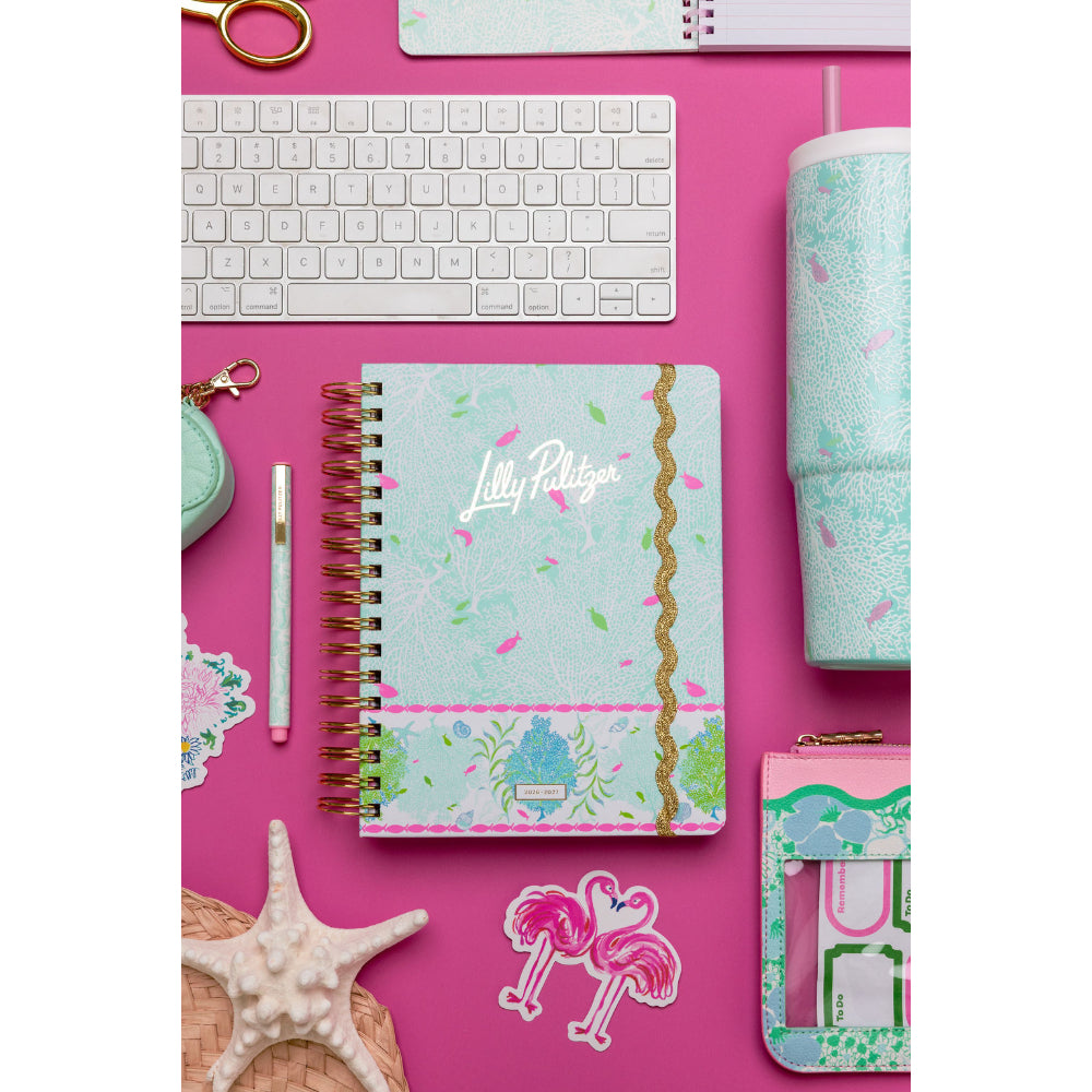 Notebook with colorful design on a pink desk with keyboard and stationery items