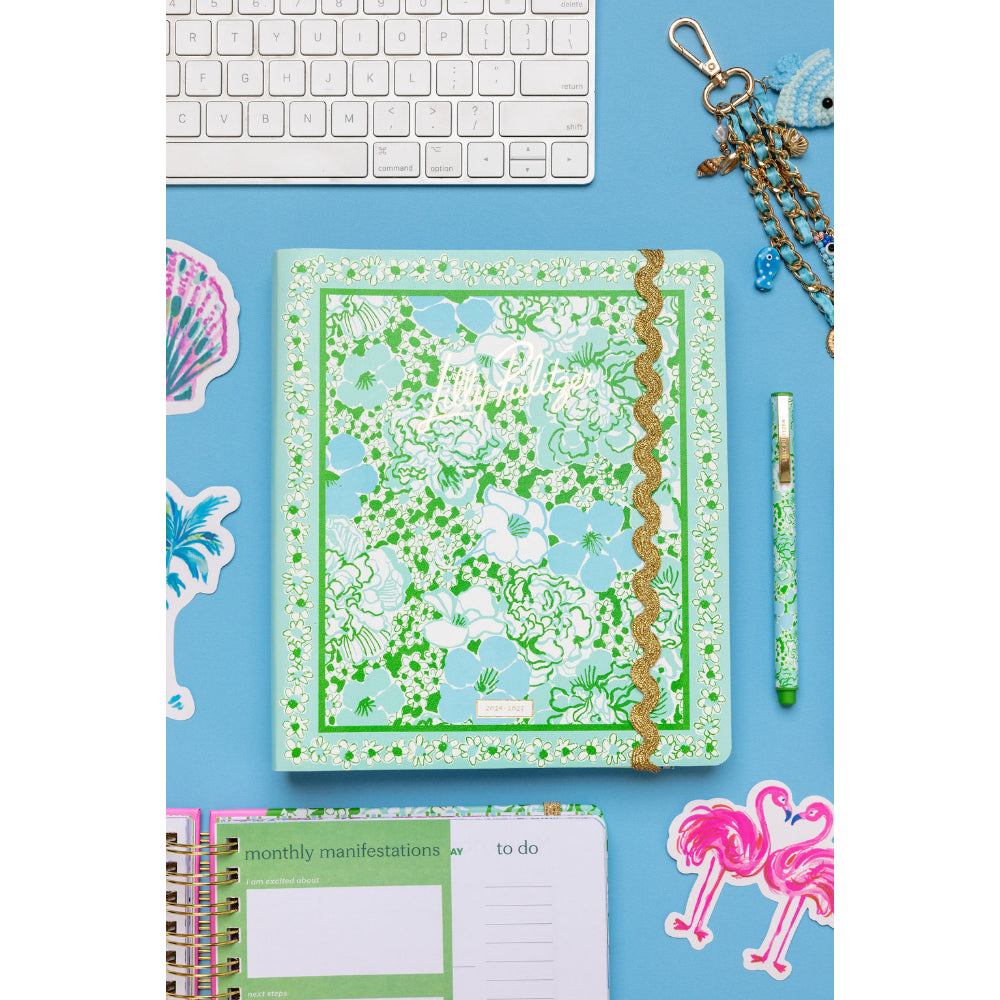 Floral notebook on a blue desk with keyboard and stationery items