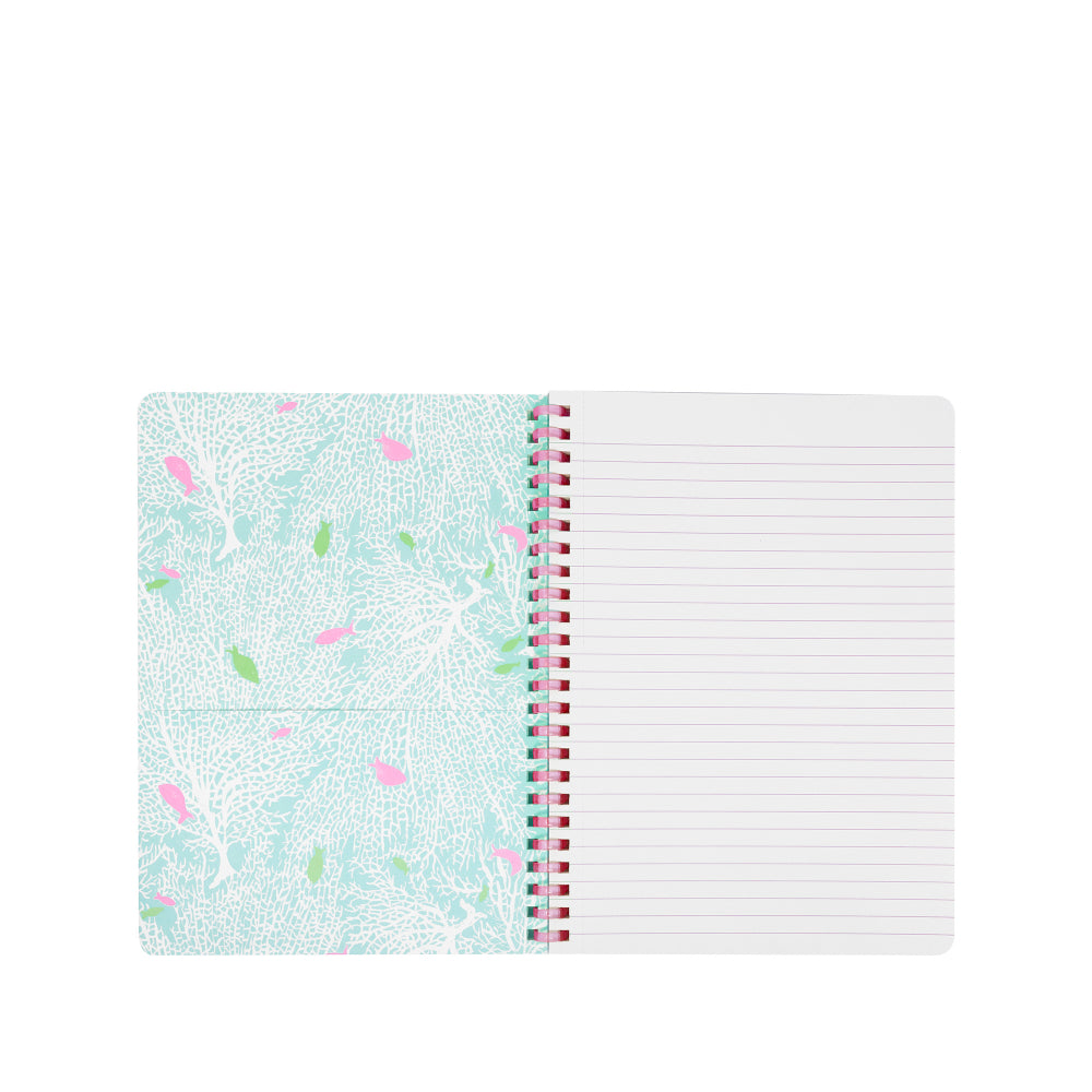 An open spiral-bound notebook with lined pages on the right and a patterned cover on the left, featuring a light blue and white coral-like design with pink and green accents.