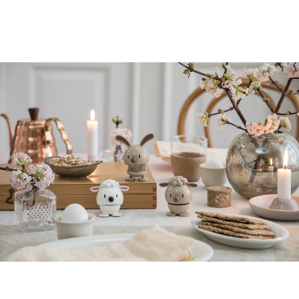 Lam shaped figurines with a spring on  a table with a sping setting on a white table cloth 