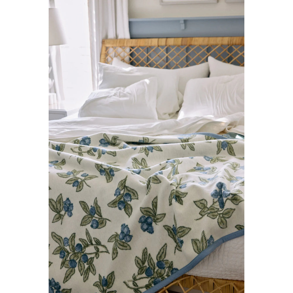 Floral patterned quilt on a bed with white pillows and a wooden headboard.