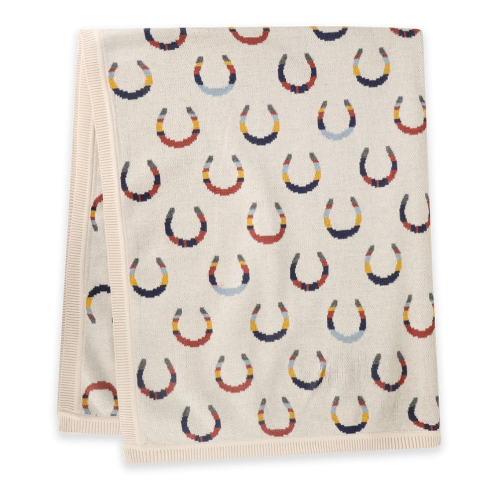 A folded cream-colored towel with a repeating pattern of horseshoes in navy, red, orange, and light blue, featuring a ribbed cream border.