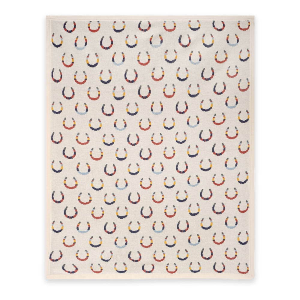 A rectangular cream-colored fabric item, likely a towel or blanket, featuring a repeating pattern of horseshoes in navy blue, red, and light blue.
