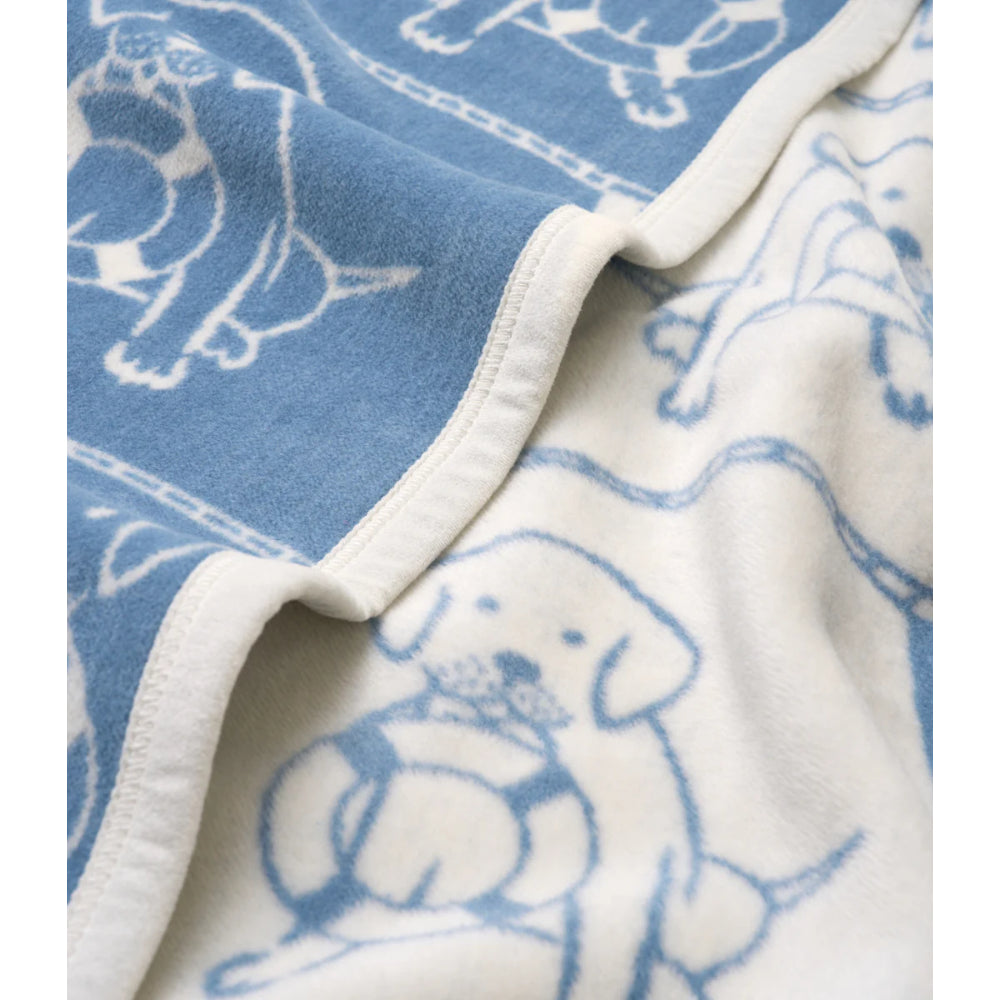 Close-up of a blue and white fabric blanket with dog illustrations