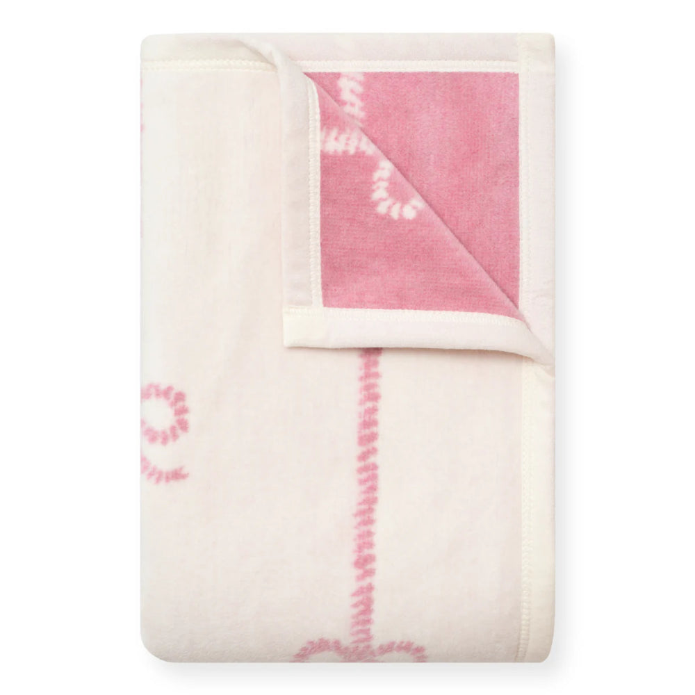 Folded blanket with pink and white patterns on a white background