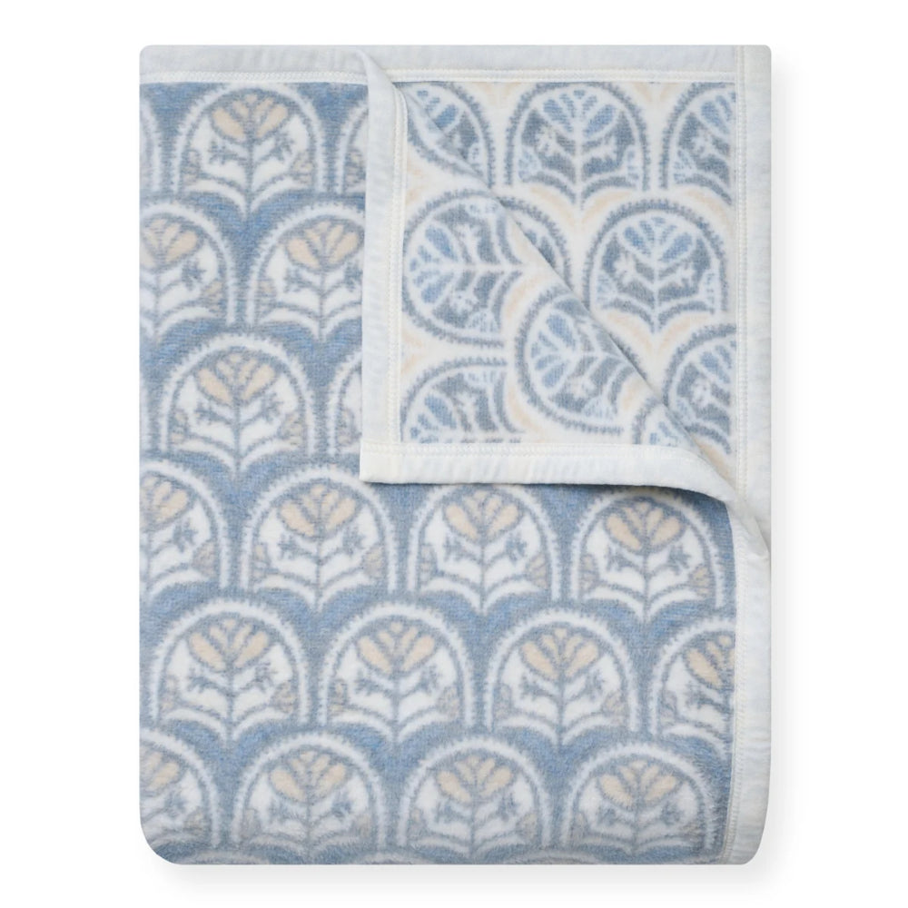 A folded baby blanket featuring a repeating blue and beige botanical arch pattern on a white background, with a soft white border.