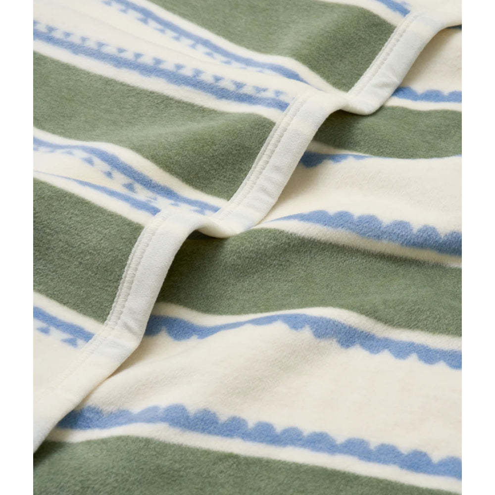 A close-up of a striped textile, likely a towel or blanket, featuring horizontal bands of sage green, cream, and light blue with a scalloped edge pattern.