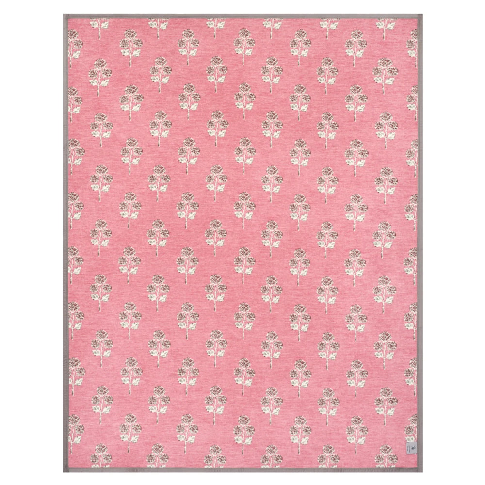 A rectangular pink area rug with a repeating floral pattern in muted gray and off-white, finished with a thin gray border.