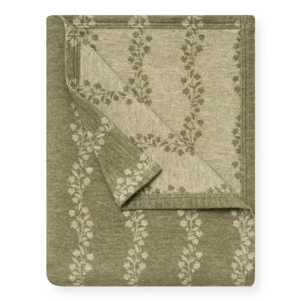 A folded throw blanket with a textured woven pattern, featuring a sage green and beige floral vine design, shown on a plain white background.