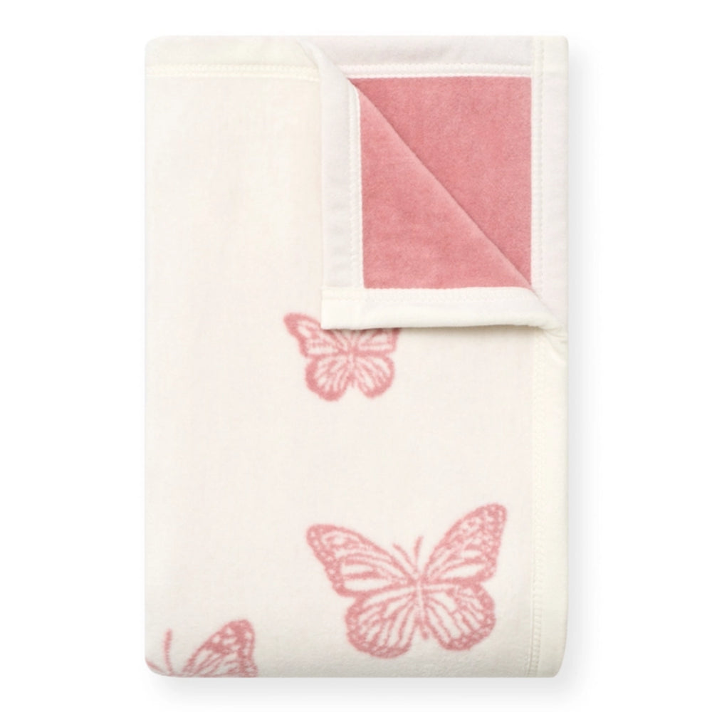 A folded cream-colored blanket with pink butterfly prints and a pink reverse side, shown on a plain white background.
