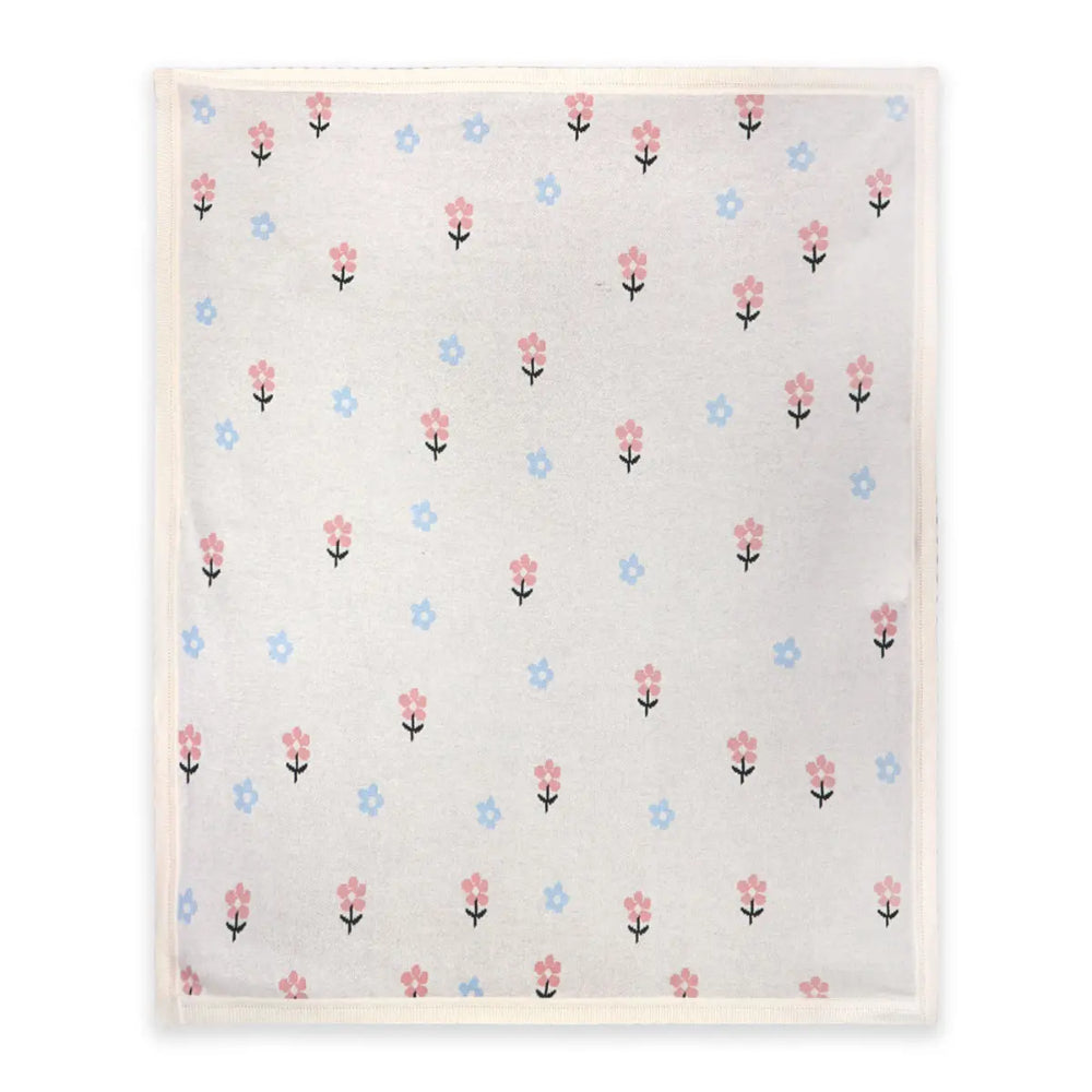 A square baby blanket with a delicate floral pattern, featuring small pink and blue flowers with black stems on a warm off-white background, finished with a soft cream-colored border.