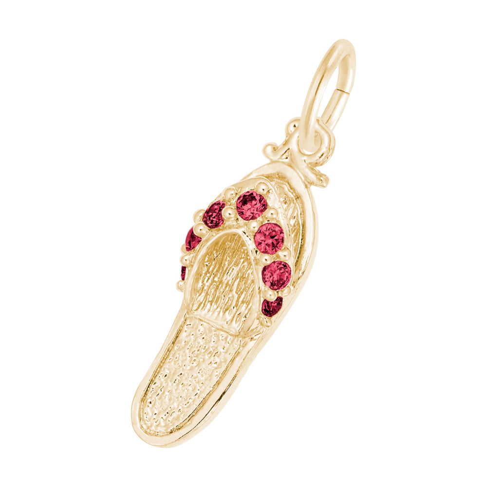 A gold charm shaped like a flip-flop sandal, featuring textured gold detailing and a row of round red gemstones along the strap, set against a plain white background.