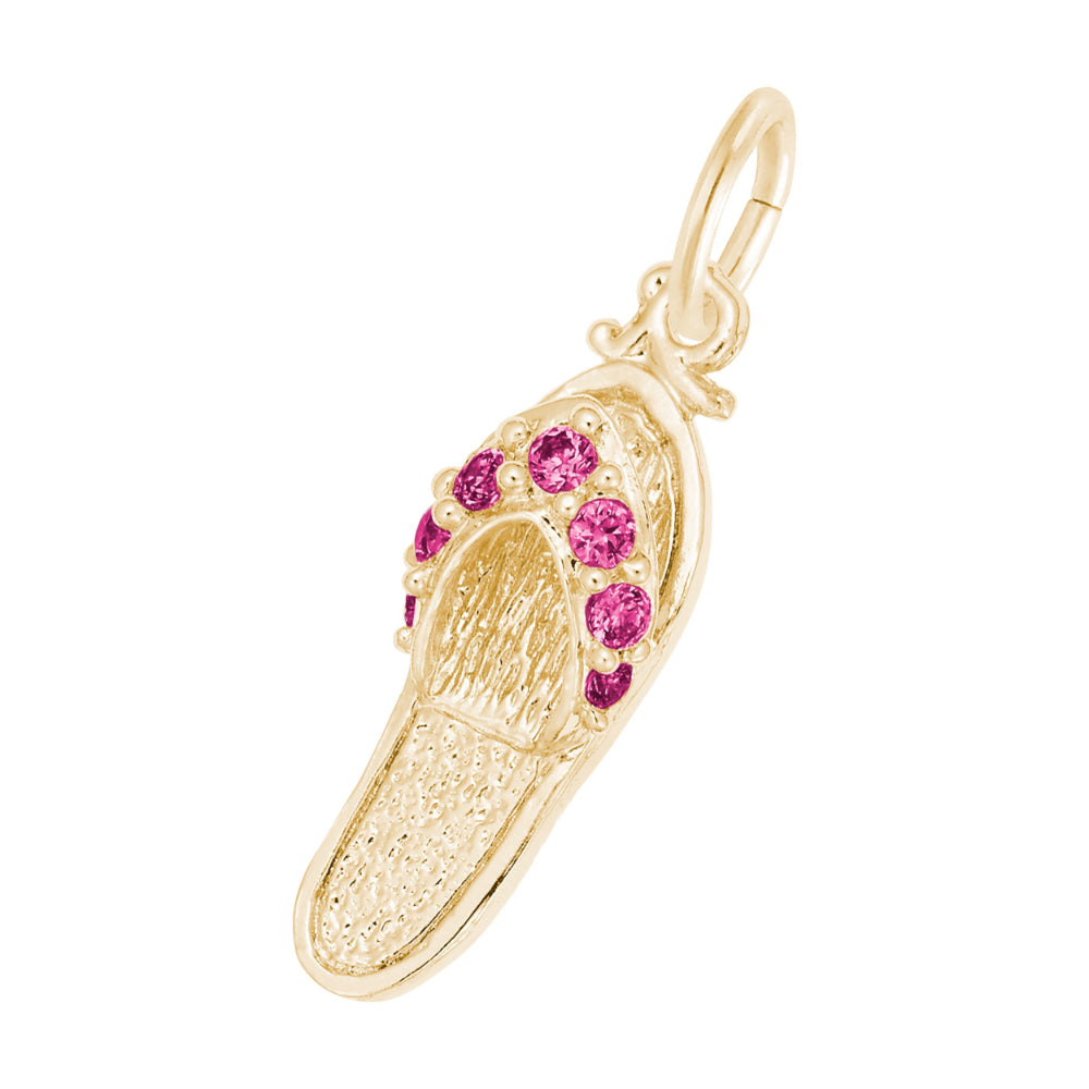 A gold charm shaped like a flip-flop sandal, featuring textured gold detailing and a row of round red gemstones along the strap, set against a plain white background.