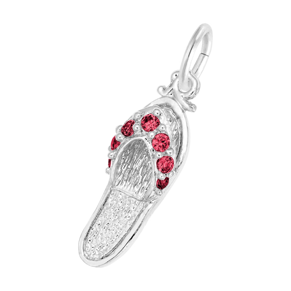 A silver charm shaped like a flip-flop sandal, featuring textured silver detailing and a row of round red gemstones along the strap, set against a plain white background.