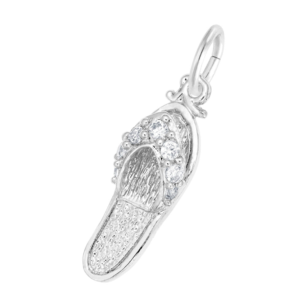 A silver charm shaped like a flip-flop sandal, featuring textured silver detailing and a row of round clear gemstones along the strap, set against a plain white background.