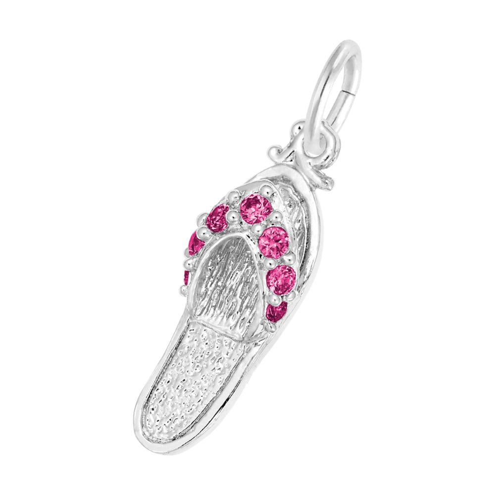 A silver charm shaped like a flip-flop sandal, featuring textured silver detailing and a row of round red gemstones along the strap, set against a plain white background.