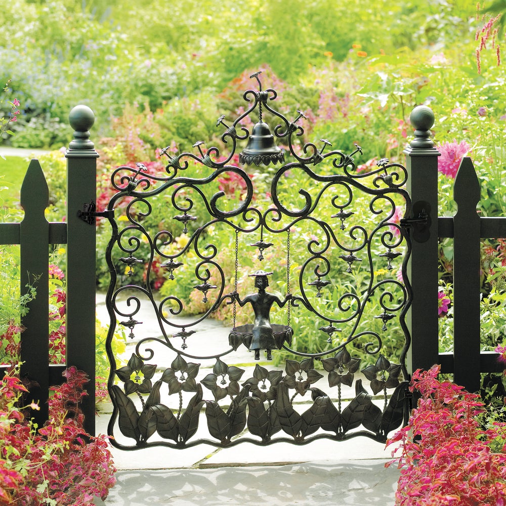 Decorative garden gate with intricate designs and floral elements in a lush garden setting.