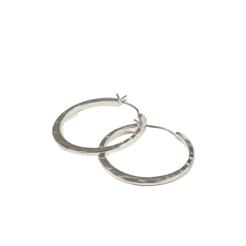 A pair of thick, hammered silver hoop earrings with a butterfly clutch back, displayed on a clean off-white background.
