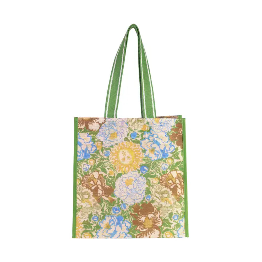 A square canvas tote bag featuring a vibrant floral and sun pattern in green, blue, yellow, and brown, with solid green handles.