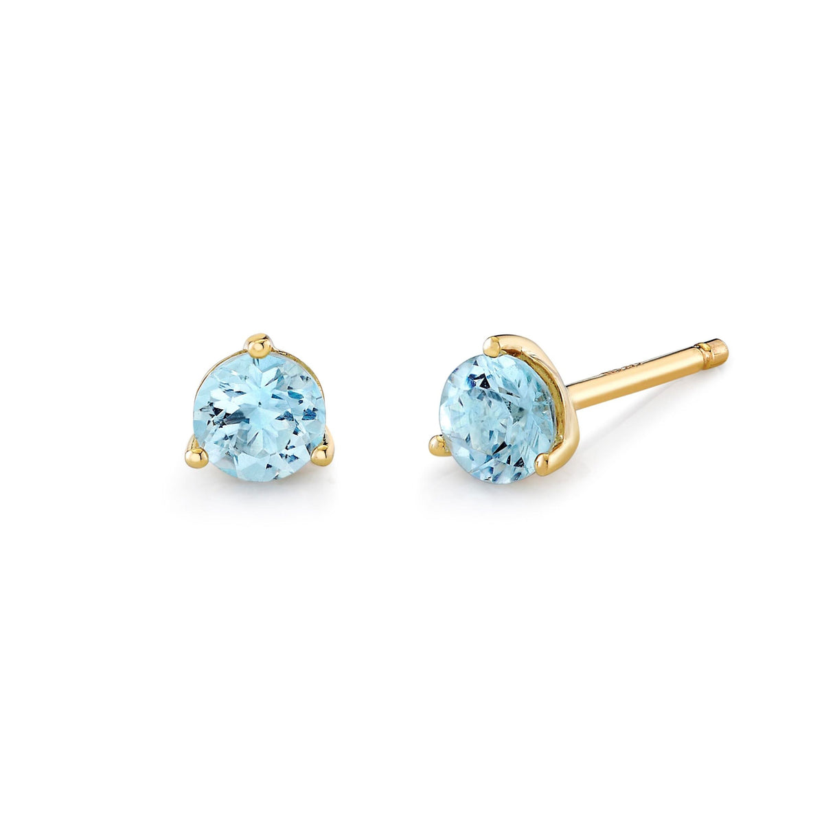 A pair of gold stud earrings with round light blue gemstones, shown on a clean white background. One earring is facing forward to show the stone and prongs, while the other is angled to show the post and backing.