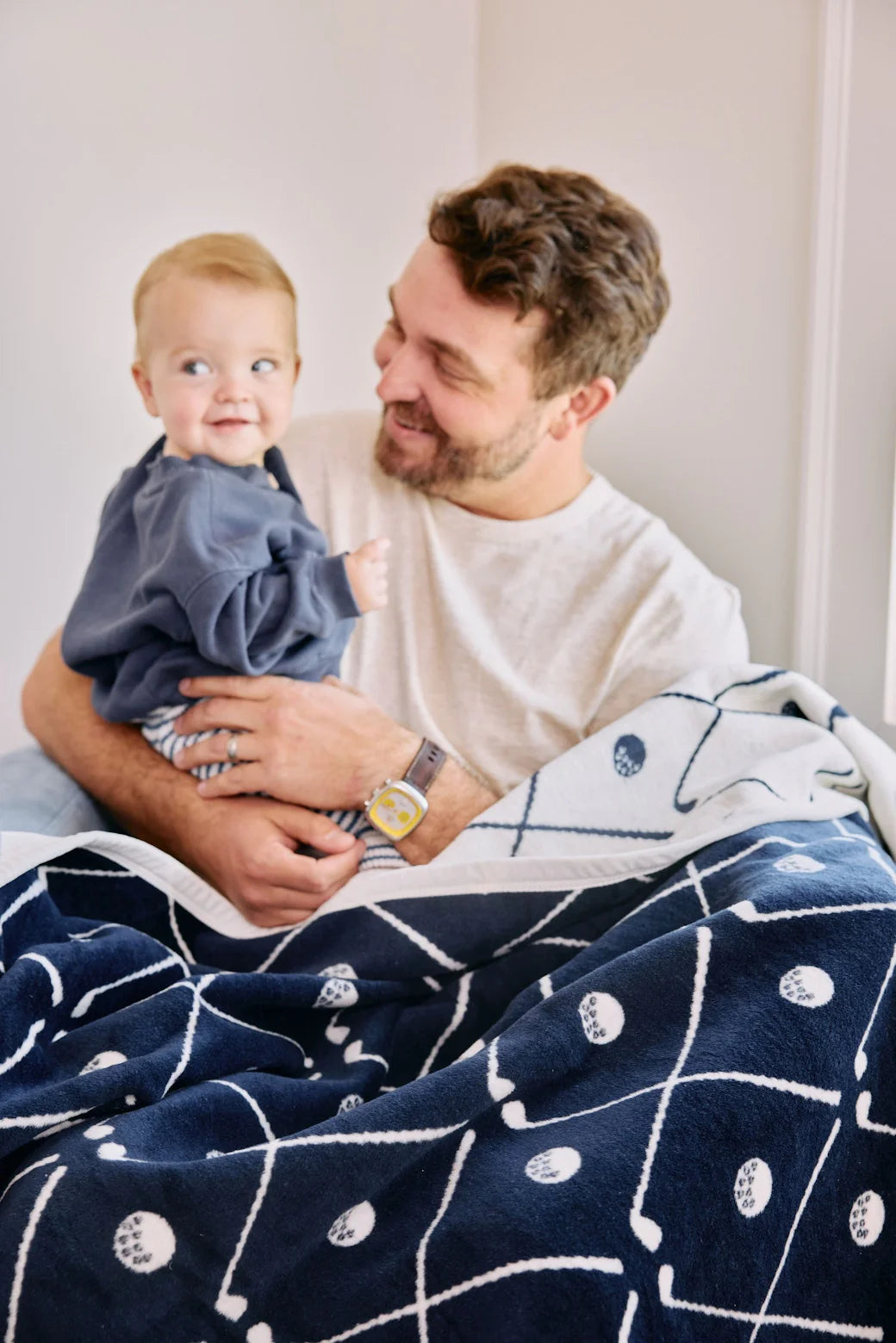 Man holding a child under a blue patterned golf blanket