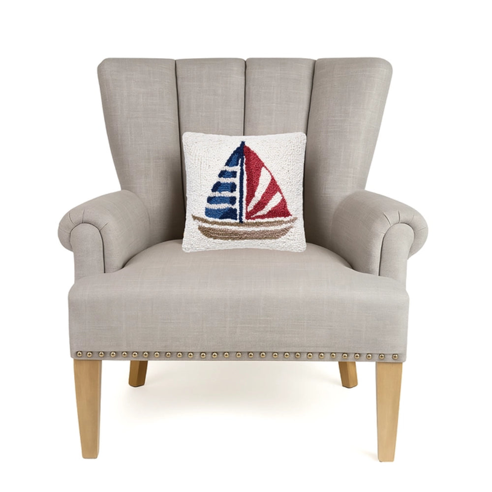 Gray armchair with a decorative pillow featuring a sailboat design on a white background.