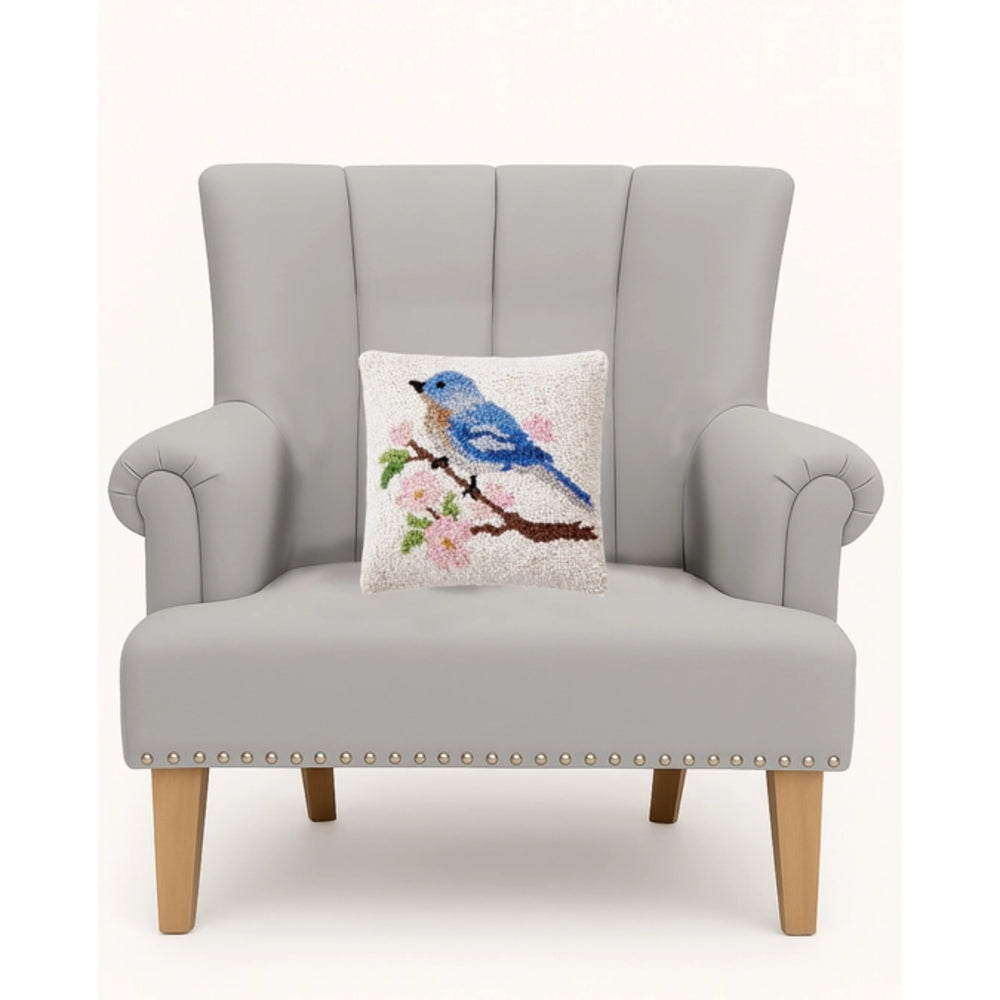 Gray armchair with a decorative pillow featuring a blue bird on a branch.
