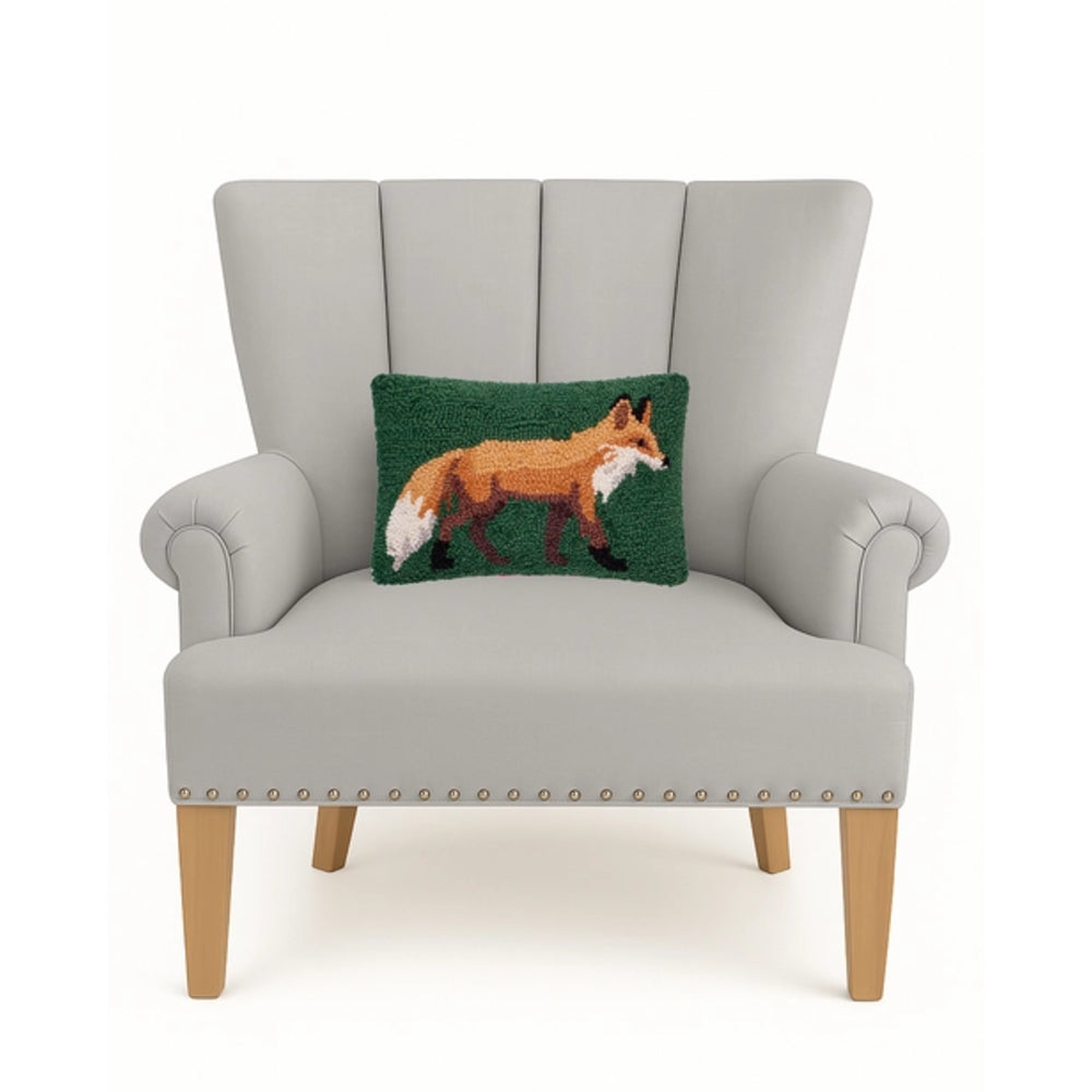 A light gray upholstered armchair with wooden legs and nailhead trim, featuring a green rectangular throw pillow with a fox design, shown against a plain white background.