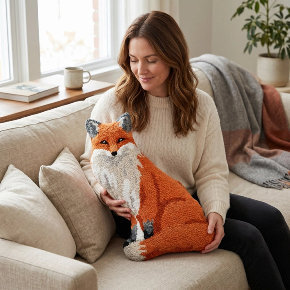 Woman holding a plush fox pillow on a couch in a cozy living room.