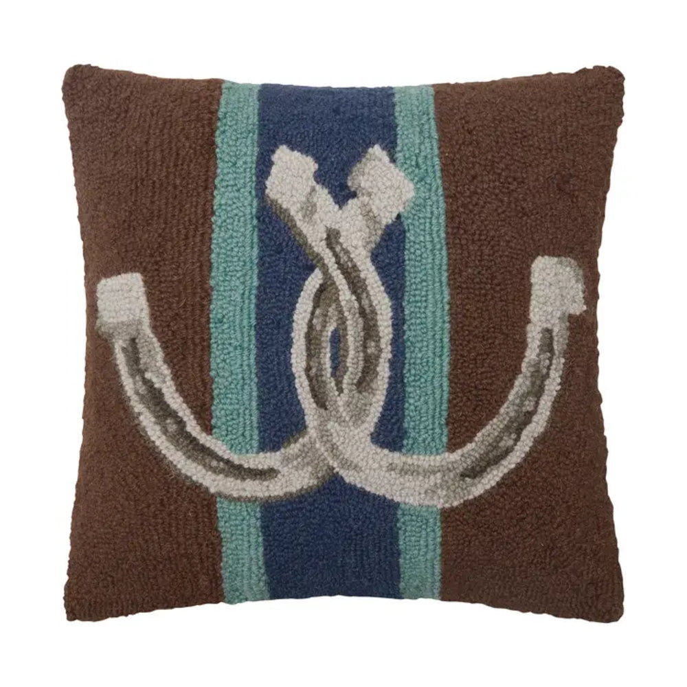 A square brown textured throw pillow featuring a central design with vertical teal and navy stripes and a large white horseshoe motif.