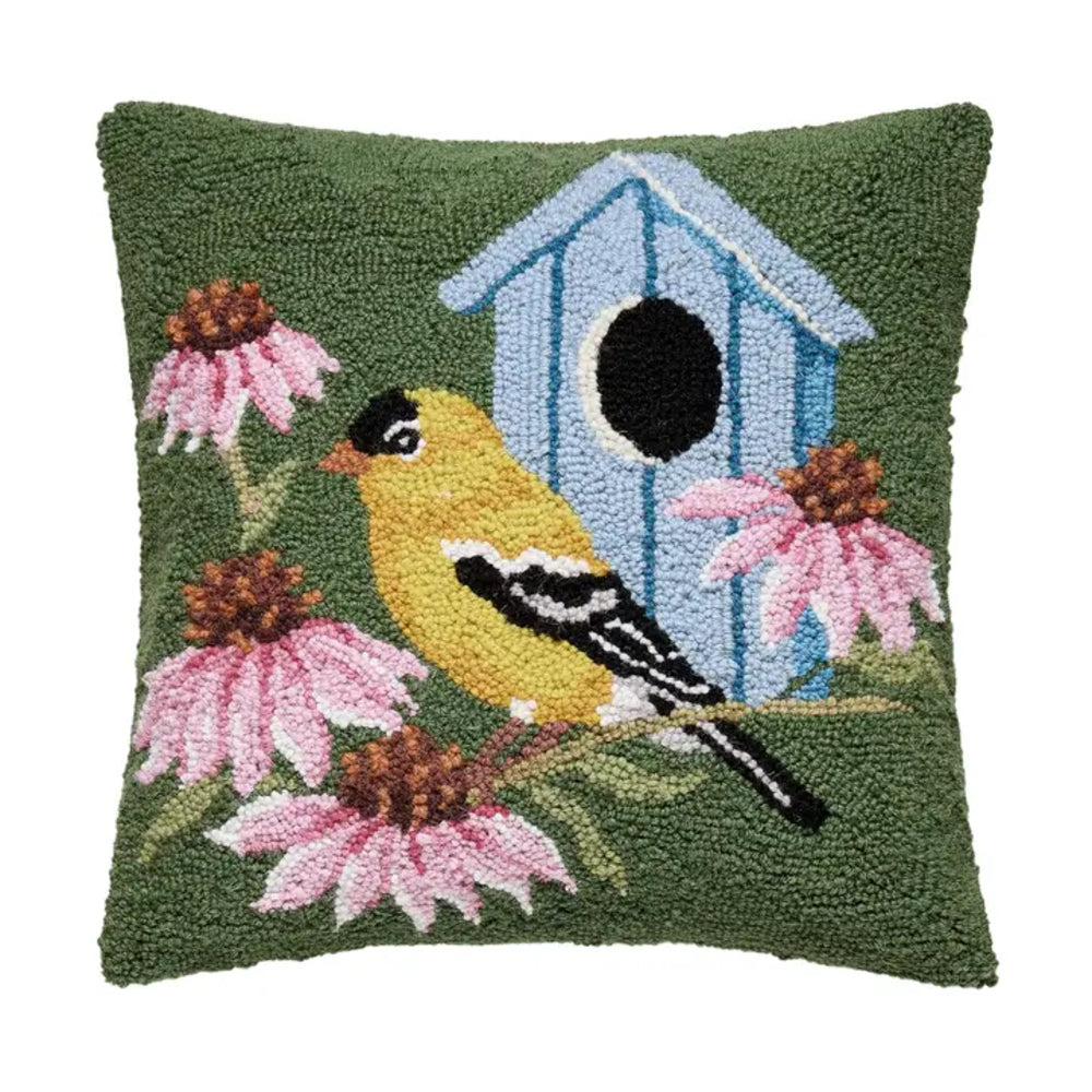 Decorative pillow with a bird, flowers, and a birdhouse design on a green background.