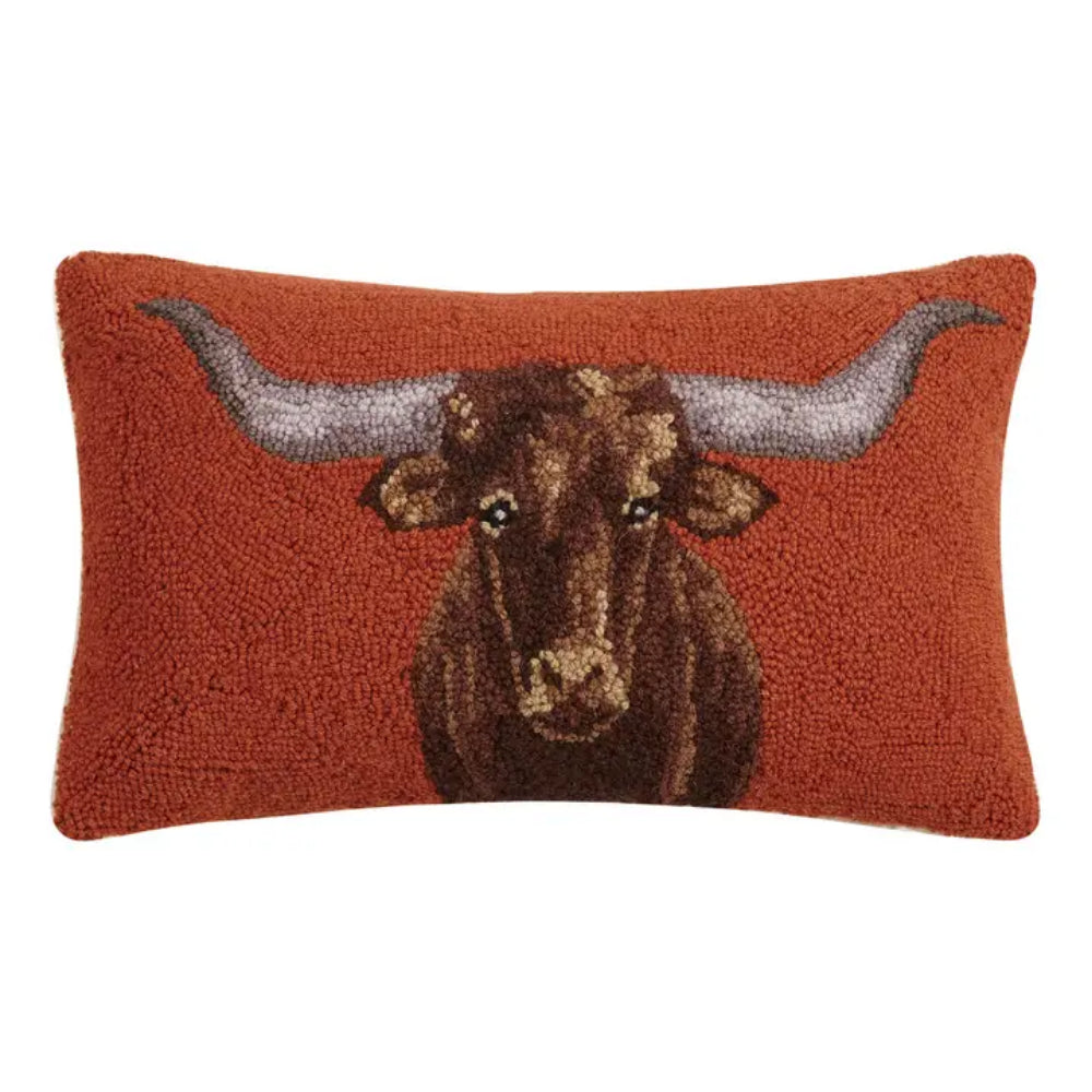 A rectangular textured throw pillow in rust orange featuring a detailed, raised tufted depiction of a brown longhorn steer's head with gray horns, shown against a plain white background.