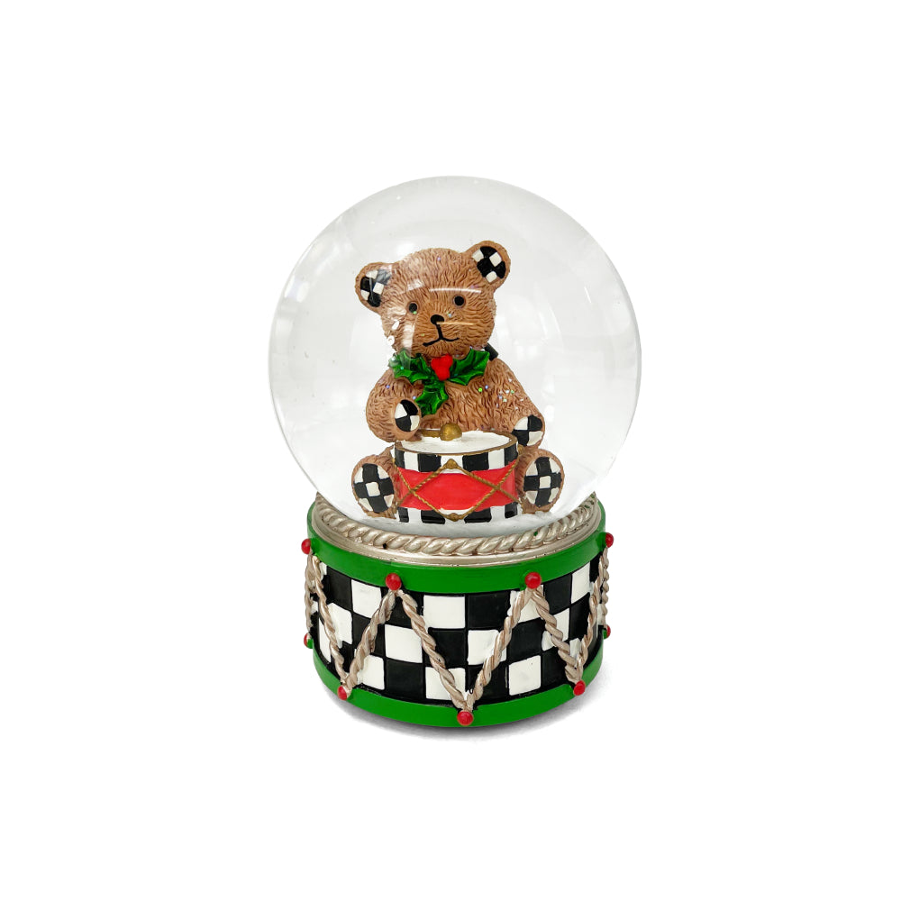 Snow globe with a teddy bear on a drum against a white background