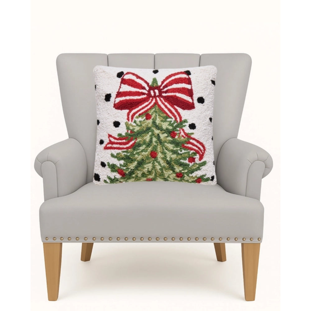 A light gray upholstered armchair with wooden legs and nailhead trim, shown against a white background with a decorative throw pillow featuring a Christmas tree and red bow motif.