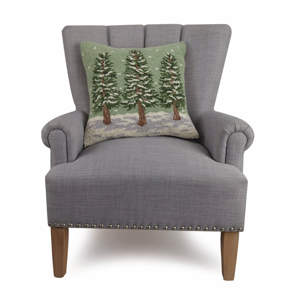 Winter Trees Hook Pillow sitting on a grey chair on a white background. 