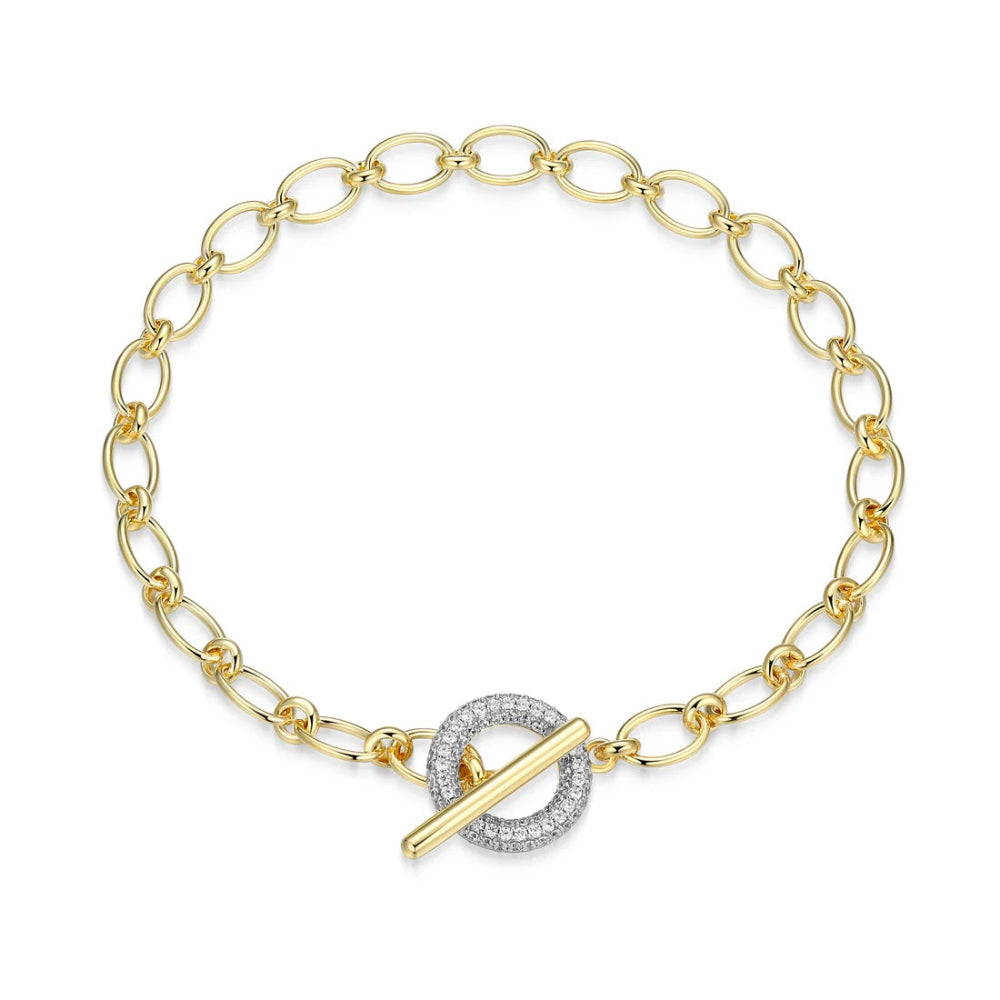 A yellow gold tone chain bracelet with a toggle clasp featuring a double-ring design, one half paved with small clear stones and the other with a gold bar,. 