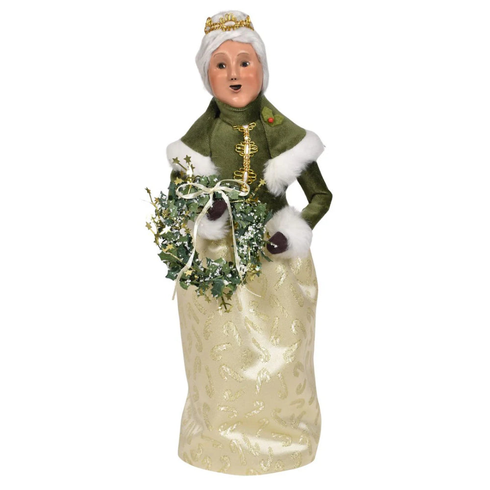 A gold and green decorative figurine of Mrs. Claus  holding a wreath on a white background