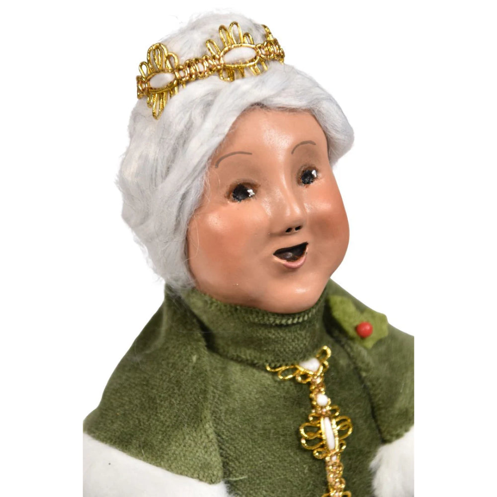 A close up of Mrs.Claus face in gold and green on a white  background