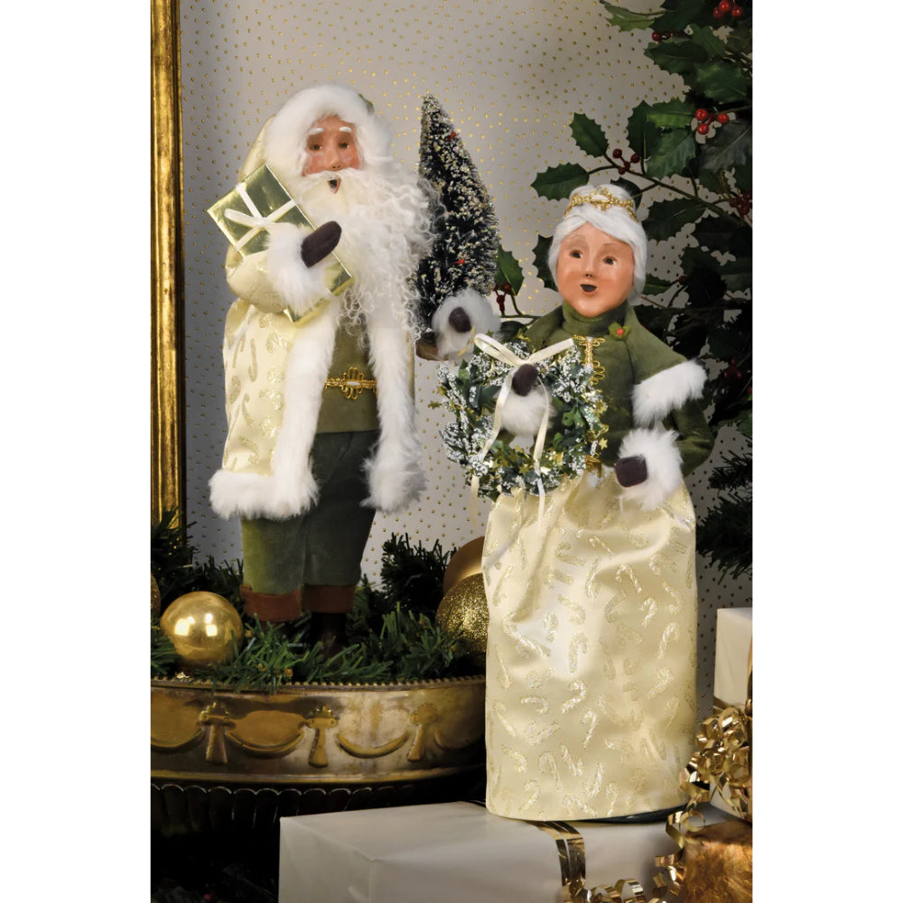 Two decorative figures of Santa Claus and Mrs. Claus  in a festive setting with Christmas decorations.
