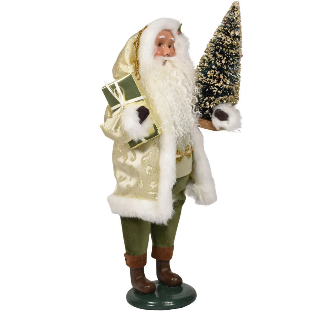 A second side photo of a decorative figure of Santa with a, green  and gold outfit, and holding a gift and tree on a white background.