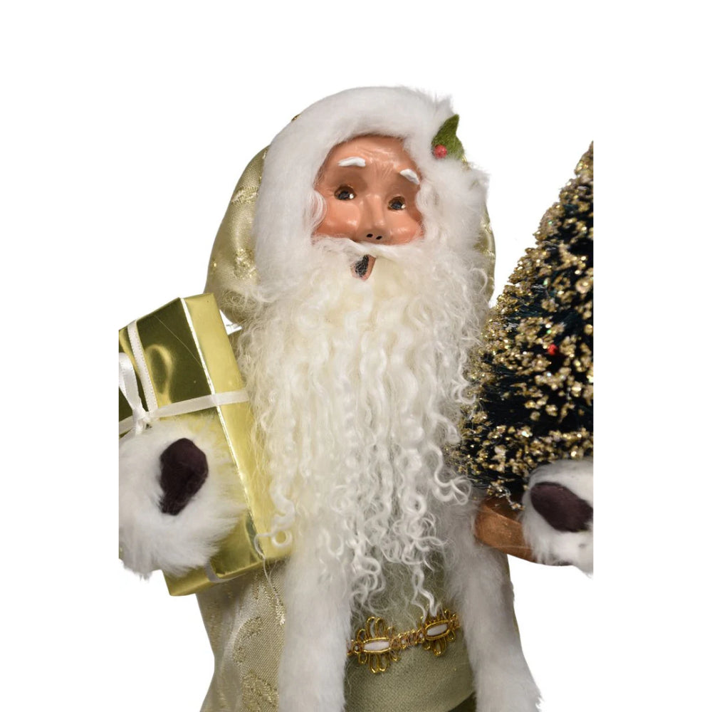 A a close up photo of a decorative figure of Santa with a, green and gold  outfit, and holding a gift and tree on a white background.