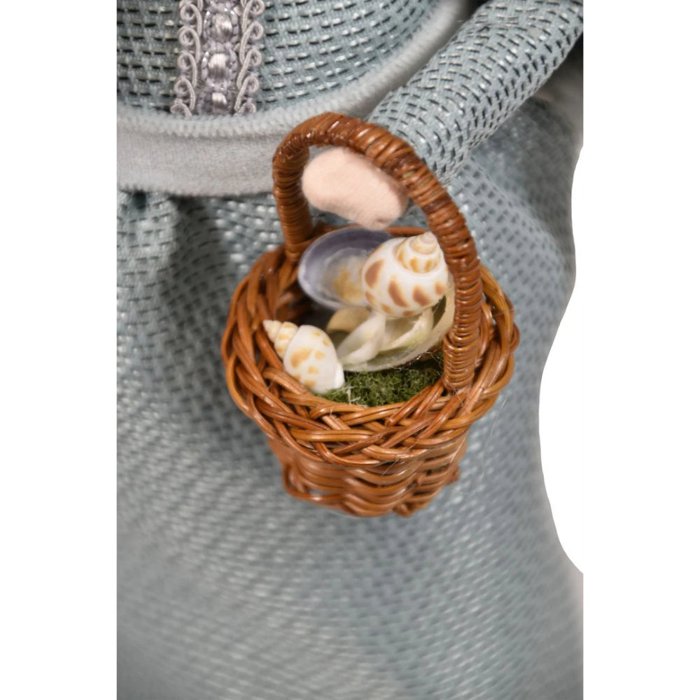 A close up photo of the basket with sea shells on a decorative figurine of a nautical mrs.claus  in traditional attire with a basket on a white background