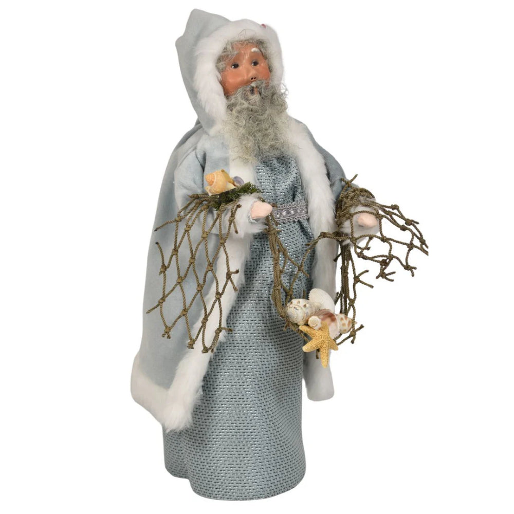 A left angled photo of the face of the decorative figure of the Nautical Santa in a gray outfit with white fur trim, holding starfish and seaweed on a white background.